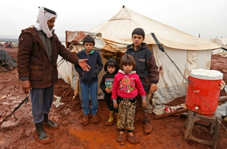 Abou Khaled pose avec ses enfants dans un camp de fortune de déplacés à Batabou, à la frontière entre les provinces syriennes d'Idleb et d'Alep, le 24 janvier 2018