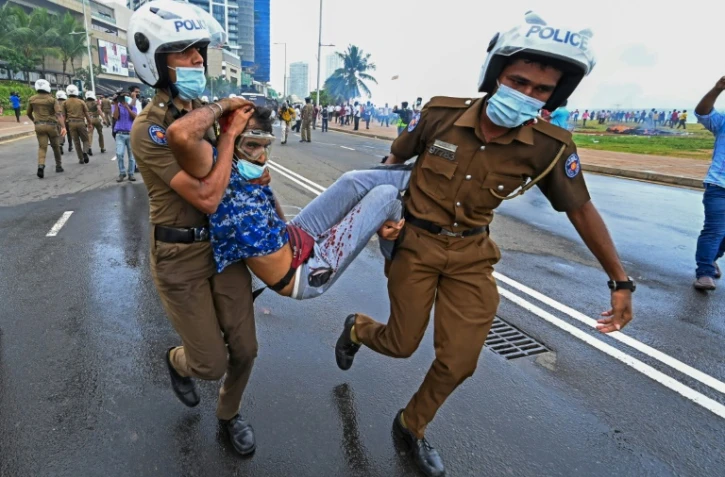 Des policiers emmènent un blessé devant la présidence srilankaise, à Colombo le 9 mai 2022