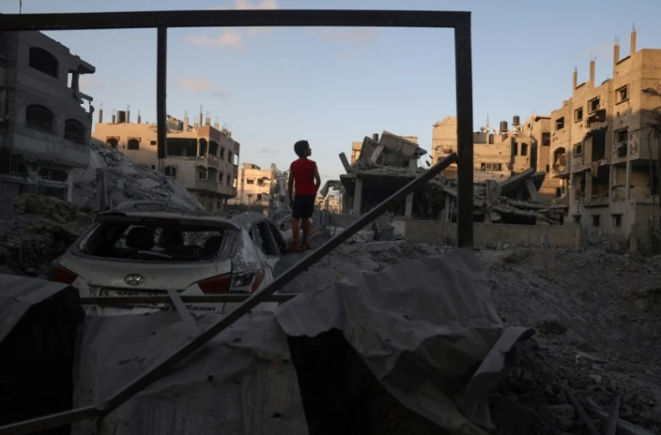 Un jeune Palestinien se tient près de gravats d'un bâtiment détruit par un bombardement israélien dans le camp de réfugiés de Nousseirat, dans le centre de la bande de Gaza, le 22 août 2024, sur fond de guerre entre Israël et le mouvement islamiste Hamas