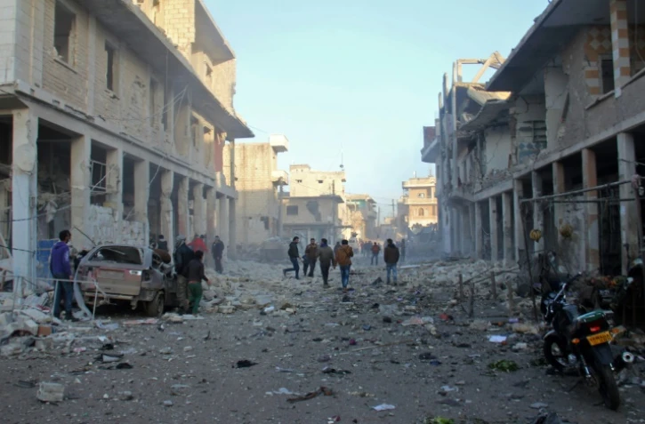 Des Syriens courent après des raids aériens dans la ville de Binnish, dans les environs d'Idleb le 12 janvier 2017