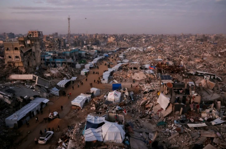 Des Palestiniens marchent près de tentes installées en pleine rue au milieu des ruines de bâtiments détruits, le 18 février 2025 à Jabalia dans la bande de Gaza