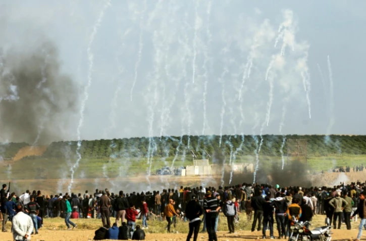 Des Palestiniens courent pour éviter des gaz lacrymogènes tirés par l'armée israélienne près de la frontière entre la bande de Gaza et Israël, le 30 mars 2018