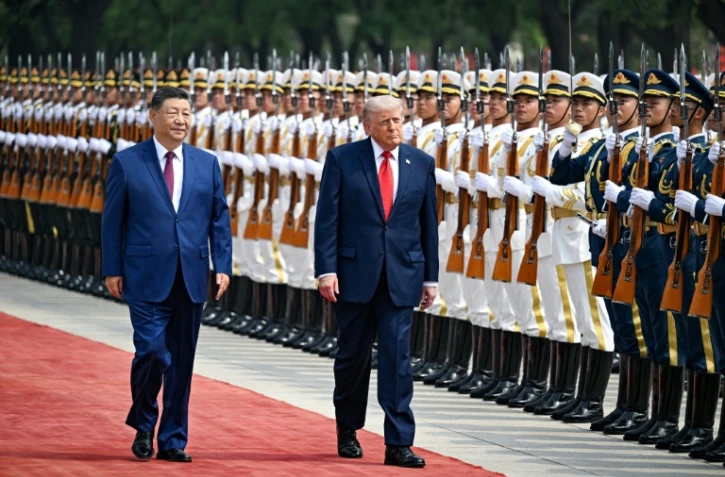 Le président américain Donald Trump (droite) et son homologue chinois Xi Jinping passent des troupes en revue, le 14 mai 2026 à Pékin