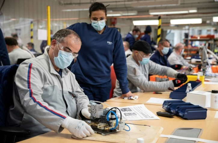 Des employés du groupe automobile PSA assemblent les pièces de respirateurs médicaux, le 15 avril 2020 à l'usine de Poissy, au nord-ouest de Paris