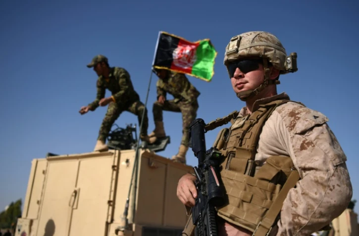 Des soldats afghans hissent le drapeau national près d'un Marine américain à la base militaire de Lashkar Gah, dans la province du Helmand, le 28 août 2017