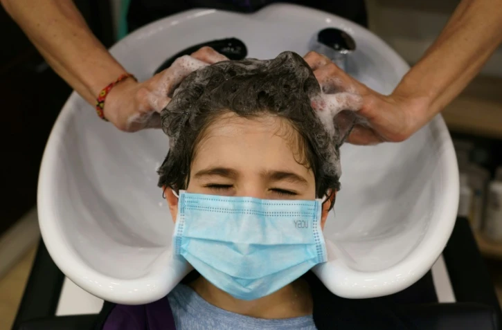 Un coiffeur espagnol lave les cheveux d'un client portant un masque à Burgos, le 4 mai 2020. 
