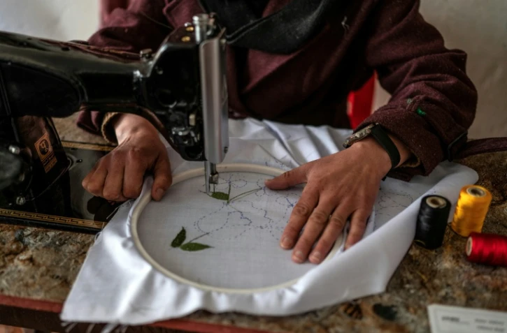 La couturière Rahima Alavi brode à la machine à coudre un tissu dans sa boutique à Bamiyan, le 26 janvier 2026 en Afghanistan