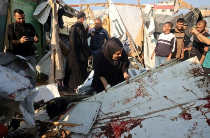 Une femme soulève une planche tachée de sang après une frappe qui a touché des tentes dans le centre de la bande de Gaza, le 9 novembre 2024