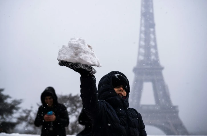 Un enfant joue avec de la neige devant la Tour Eiffel, le 5 février 2018 à Paris.