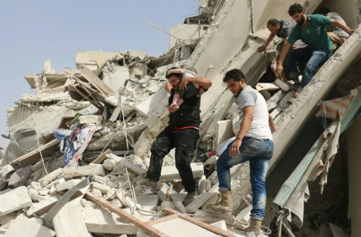 Un habitant évacue un enfant des décombres d'un immeuble après des raids aériens, le 21 septembre 2016 à Alep, en Syrie