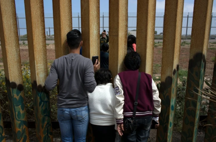 La famille Rosete-Quintana se retrouve des deux côtés de la frontière entre les Etats-Unis et le Mexique, sous les yeux d'un agent américain, le 2 juillet 2016 à Tijuana