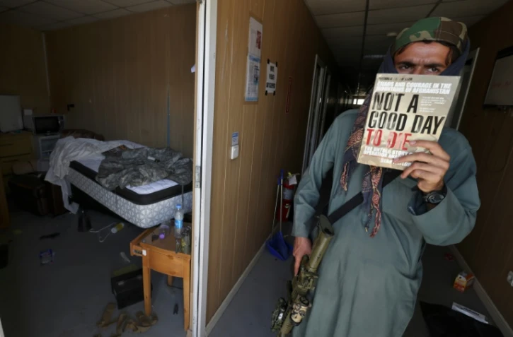 Un combattant taliban montre un exemplaire du livre "Not a Good Day to Die", dans une baraque militaire de l'aéroport de Kaboul abandonnée par les Américains, le 14 septembre 2021