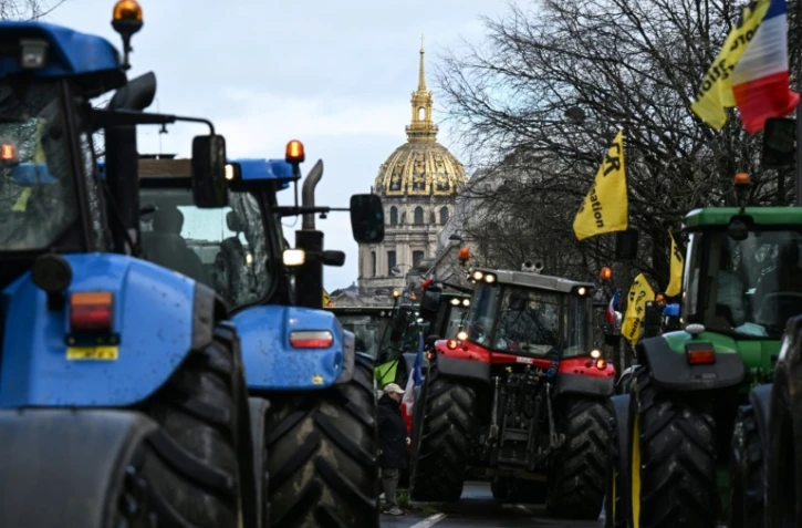 Des agriculteurs français conduisent des tracteurs lors d'une manifestation organisée par le syndicat agricole Coordination Rurale, avec en arrière-plan le dôme de l'Hôtel des Invalides, dans l'ouest de Paris, le 23 février 2024