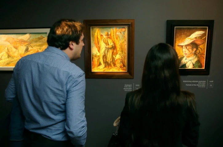 Deux personnes observent des oeuvres de Samuel Bak, peintre et survivant de l'Holocauste, à Vilnius, le 20 novembre 2017
