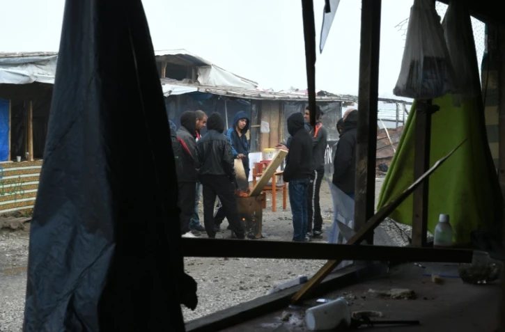Des migrants de la "Jungle" de Calais autour d'un brasero pour se réchauffer, le 23 octobre 2016, à la veille du démantèlement du campement