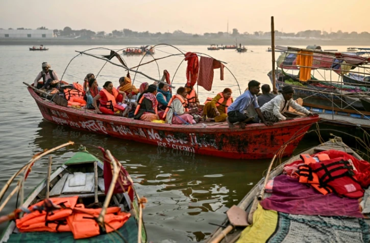 Des pèlerins hindous à bord d'une barque en bois lors du pèlerinage de la Kumbh Mela à Prayagraj, le 31 janvier 2025 en Inde