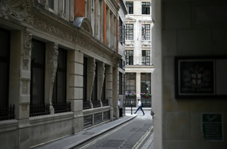 Un piéton solitaire marche dans une rue déserte de la City à Londres le 6 août 2020 pendant l'épidémie de coronavirus