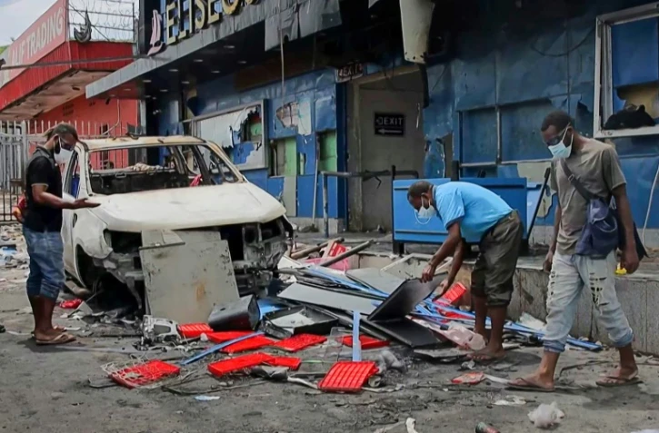 Image tirée d'une vidéo de l'AFPTV montrant des habitants déblayant des débris dans une rue de Port Moresby après des émeutes, le 11 janvier 2024 en Papouasie-Nouvelle-Guinée 