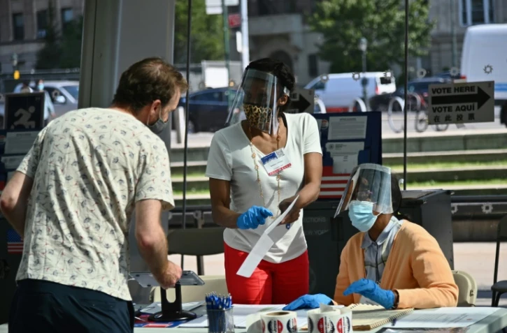 Des employées et volontaires d'un bureau de vote portent des équipements de protection contre le nouveau coronavirus lors de la primaire démocrate de New York, le 23 juin 2020 au Musée de Brooklyn
