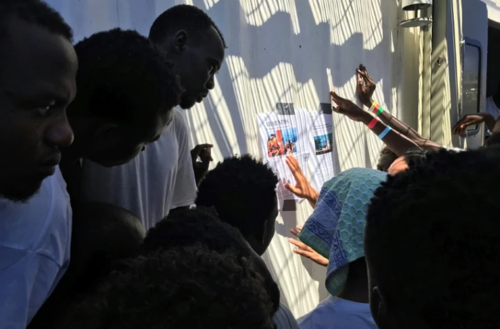 Des migrants recueillis par le navire Ocean Viking lisent des articles de presse les concernant, le 21 août 2019