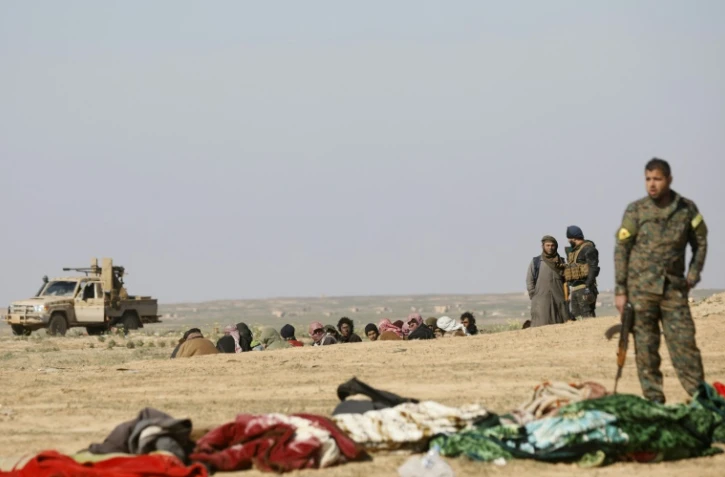 Un combattant des Unités de protection du peuple (YPG) kurdes attend le démarrage d'une fouille de prisonniers, près de Baghouz, en février 2019