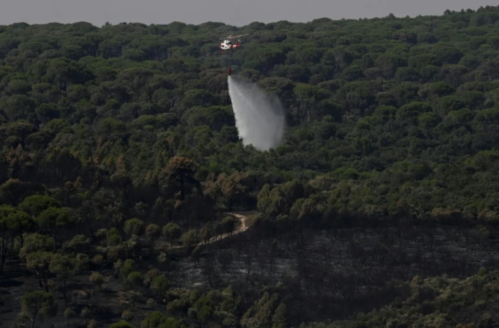 Un hélicoptère de lutte contre les incendies largue de l'eau pour rafraîchir une zone touchée par des feux de forêt à l'ouest de Madrid, le 28 juillet 2026