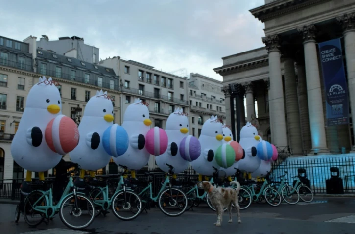 Des mascottes représentant la mouette "Boogi" se tiennent sur des vélos devant le Palais Brongniart à Paris, le 24 novembre 2023, pour marquer la candidature de la ville sud-coréenne de Busan à l'Exposition universelle de 2030