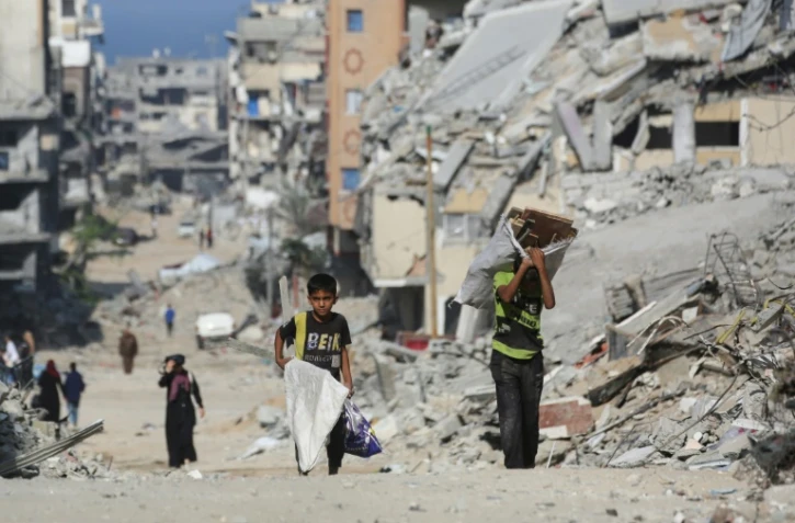 Des enfants portent du bois parmi les décombres dans le camp palestinien de Al-Shatee, dans l'est de la bande de Gaza, le 8 novembre 2025