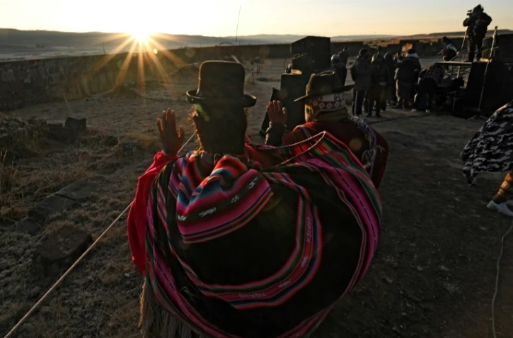Des Indiens Aymaras lèvent les paumes au ciel pour recevoir les premiers rayons du soleil lors de la célébration du Nouvel An Aymara à Tiwanaku, en Bolivie, le 21 juin 2022