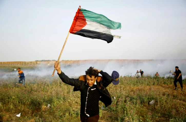Un Palestinien brandissant un drapeau lors d'une manifestation à la frontière entre la bande de Gaza et Israël le 4 avril 2018