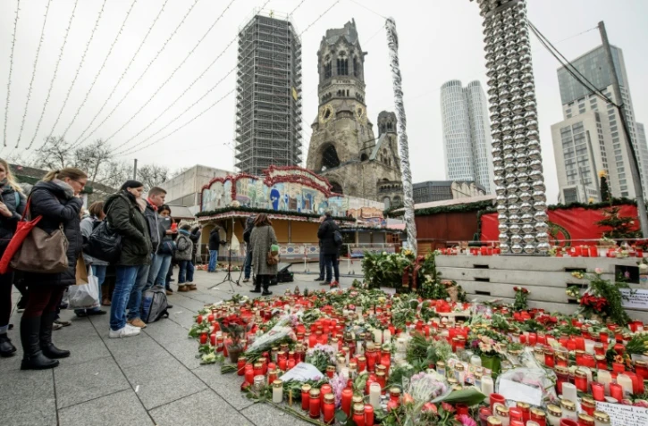 Des personnes se recueillent devant un parterre de fleurs et des messages en hommage aux victimes d'une attaque près d'un marché de Noël à Berlin, le 21 décembre 2016 en Allemagne