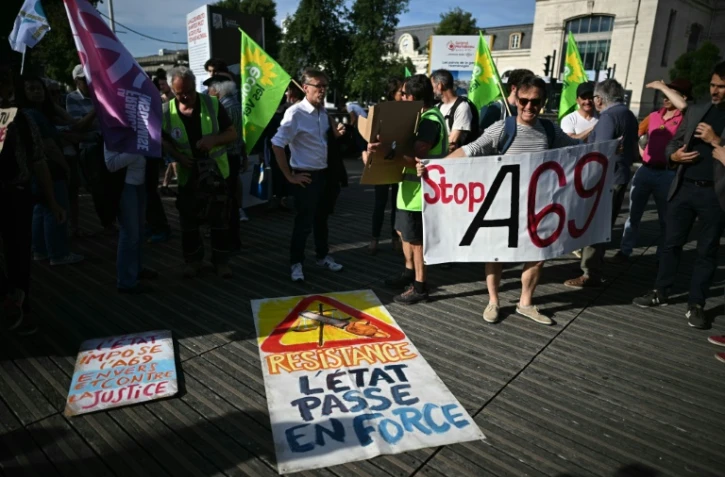 Des opposants au projet d'autoroute A69 entre les villes de Castres et de Toulouse se rassemblent à côté d'une pancarte portant l'inscription "Résistance, l'État force le passage" lors d'un rassemblement devant la gare de Toulouse, dans le sud-ouest de la France, le 28 mai 2025