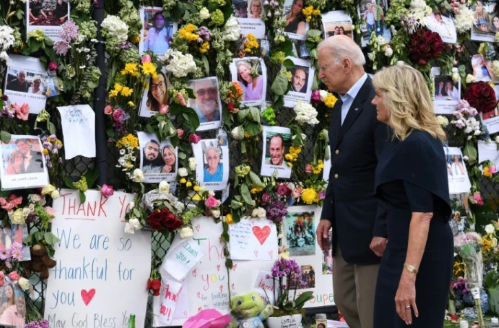 Le président américain Joe Biden et sa femme Jill Biden se recueillent devant un mur du souvenir en hommage aux 18 personnes décédées et aux 140 toujours portées disparues dans l'effondrement d'un immeuble, le 2 juillet 2021 à Surfside, en Floride