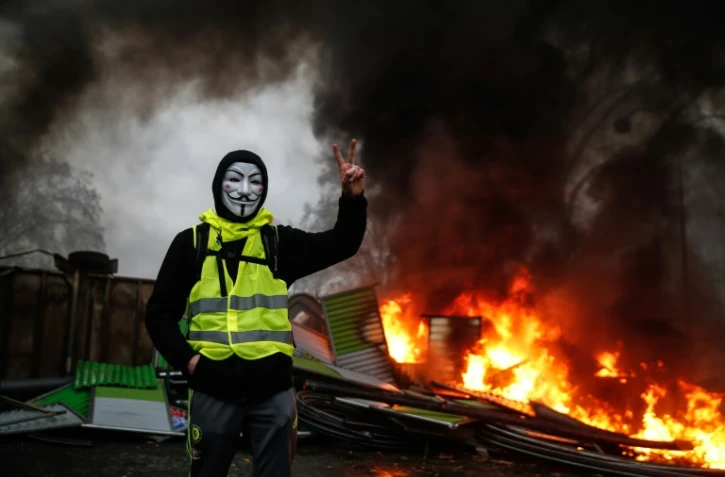 Un manifestant portant un gilet jaune et un masque près d'une barricade en feu, à Paris le 1er décembre 2018