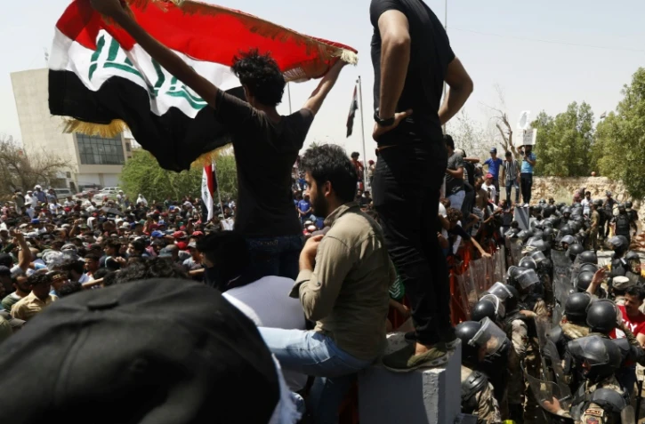 Un manifestant irakien brandit le drapeau national lors d'un rassemblement à Bassora, le 15 juillet 2018 