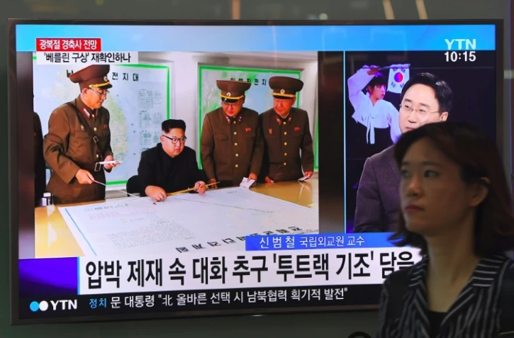Une femme passe à Séoul devant des écrans montrant le leader nord-coréen Kim Jong-Un le 15 août 2017 