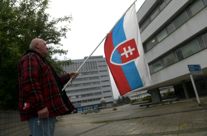Un partisan du gouvernement avec un drapeau slovaque, le 17 mai 2024, devant l'hôpital où est soigné le Premier ministre Robert Fico, en état grave après une tentative de meurtre quatre jours plus tôt