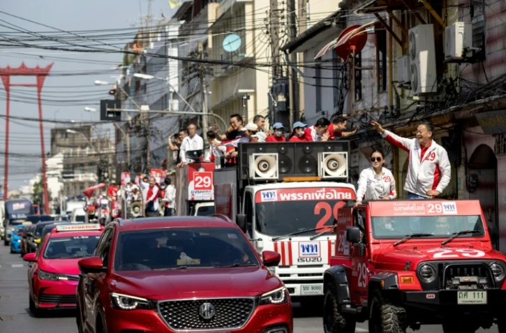 Les candidats Paetongtarn Shinawatra (2e à d.) et Srettha Thavisin (d) dans un Jeep rouge en campagne à Bangkok à la veille des élections législatives, le 13 mai 2023