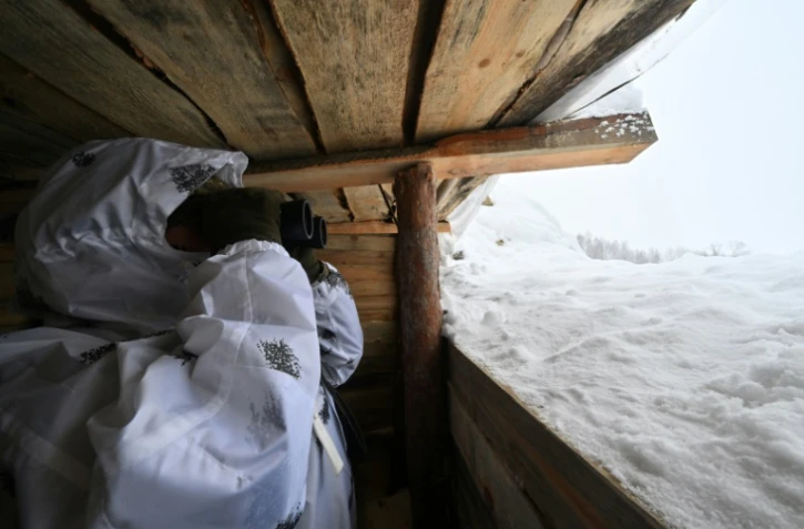 Un garde-frontière ukrainien scrute à la jumelle la zone frontalière avec le Bélarus, dans la région de Tcherniguiv (nord) le 23 janvier 2024