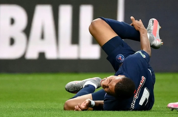 L'attaquant du Paris SG Kylian Mbappé se tient la cheville droite après avoir subi une faute lors de la finale de Coupe de France contre Saint-Etienne le 24 juillet 2020 au Stade de France à Saint-Denis