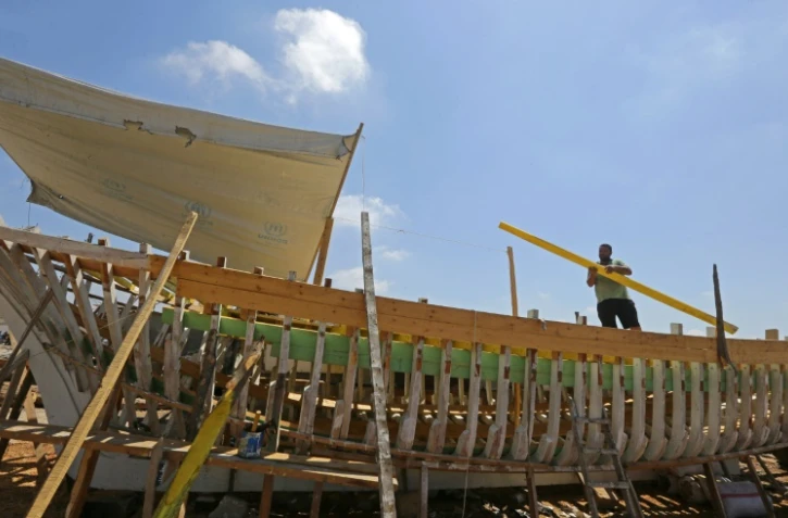 Le Syrien Khaled Bahlawan construit à la main un bateau en bois au bord de l'île d'Arwad, dans l'ouest de la Syrie, un artisanat que sa famille veut préserver, le 24 juillet 2022
