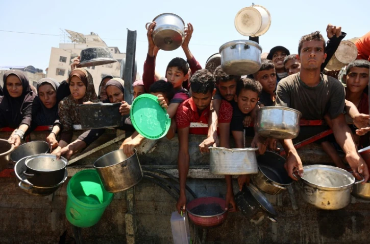 Des Palestiniens affamés attendent de recevoir une ration de soupe de lentilles lors d'une distribution alimentaire à Gaza, le 2 août 2025