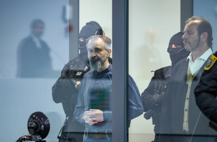 L'accusé saoudien Taleb Jawad al-Abdulmohsen (c) dans le box en verre pare-balle de la salle d'audience provisoire de Magdebourg, lors de son procès pour avoir foncé avec un SUV dans la foule d'un marché de Noël fin 2024, le 26 juin 2026 dans l'est de l'Allemagne
