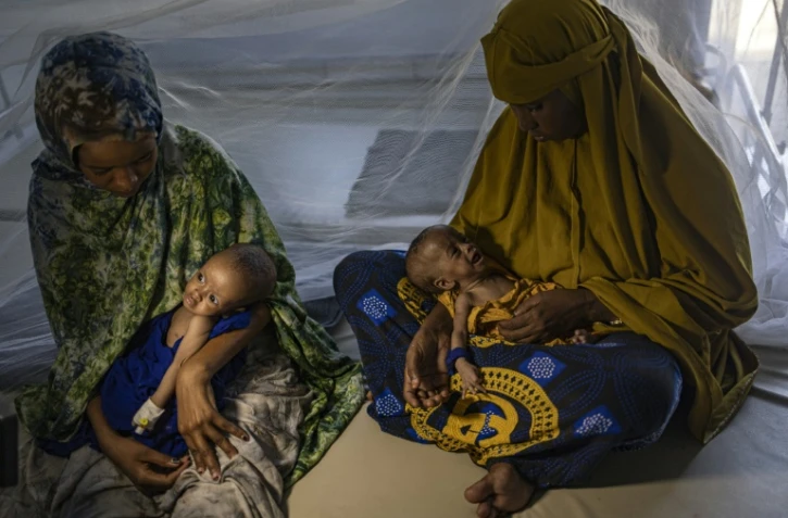 Des femmes somaliennes récemment déplacées tiennent dans leurs bras leurs bébés souffrant de malnutrition sévère dans un centre de santé, à Kismayo, le 22 avril 2026 