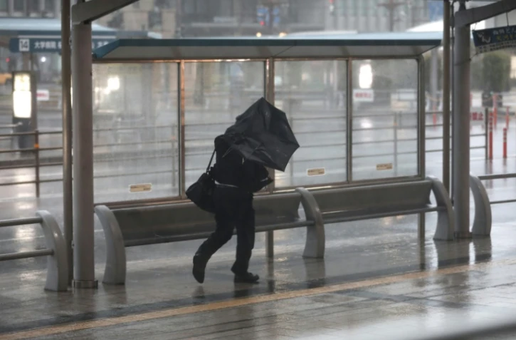 Un homme s'abrite des fortes précipitations causées par le typhon Trami à Kagoshima (sud-ouest du Japon) le 30 septembre 2018.