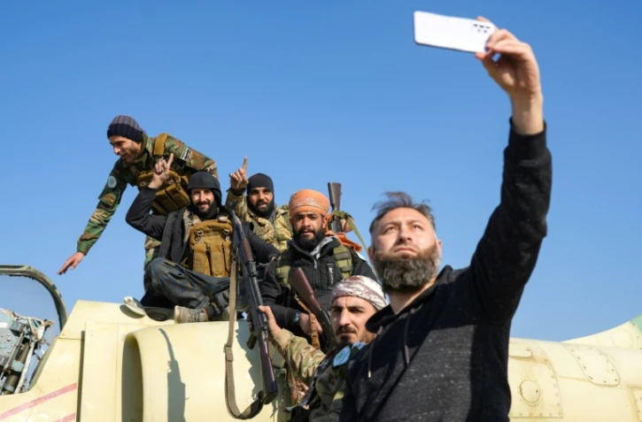 Des rebelles posent pour une photo sur un avion de l'armée syrienne dans la base aérienne de Kweyris, dans l'est de la province septentrionale d'Alep, le 3 décembre 2024 