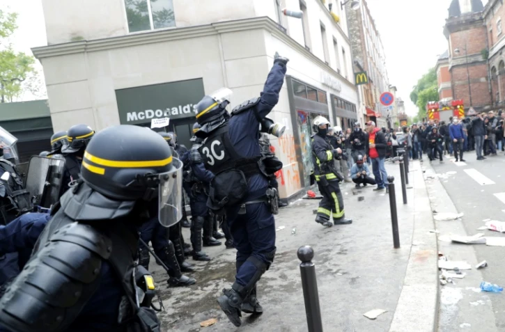 Un CRS lance une grenade lacrymogène contre des manifestants en marge du défilé syndical du 1er mai 2018 à Paris