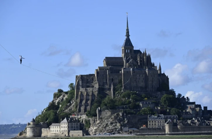 Le funambule Nathan Paulin sur une slackline de 2.200 mètres de long reliant une grue à l'abbaye du Mont Saint-Michel, le 24 mai 2022