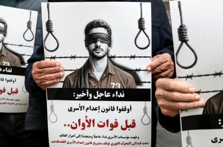 Des manifestants brandissent des pancartes sur lesquelles on peut lire "Appel urgent et final : arrêtez l'application de la loi sur les prisonniers avant qu'il ne soit trop tard" devant les locaux de la Croix-Rouge à Ramallah, en Cisjordanie occupée par Israël, le 31 mars 2026