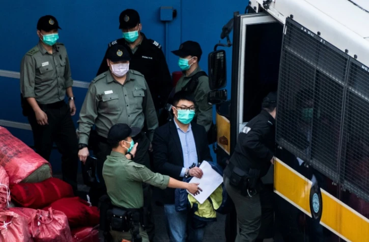 Le militant pro-démocratie Ben Chung (c) escorté par la police lors d'un transfert, le 2 mars 2021 à Hong Kong